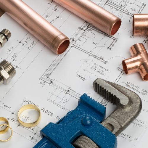 Plumbing fittings, and wrenches on top of blueprints. 